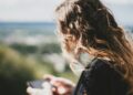 Jonge vrouw met lang krullend haar kijkt op haar smartphone